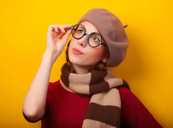 Rothaarige Mädchen mit Brille und Schal auf gelbem Hintergrund. — Stockfoto