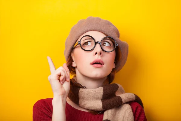 Rödhårig flicka i glasögon och halsduk på gul bakgrund. — Stockfoto