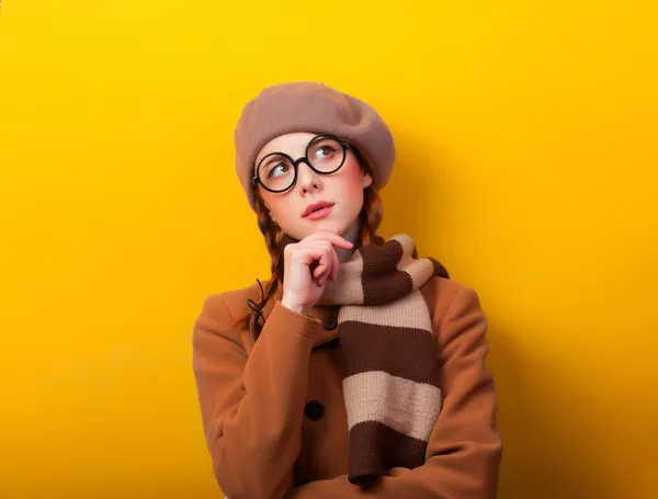 빨강 머리 소녀 코트와 노란색 배경에 스카프. — 스톡 사진