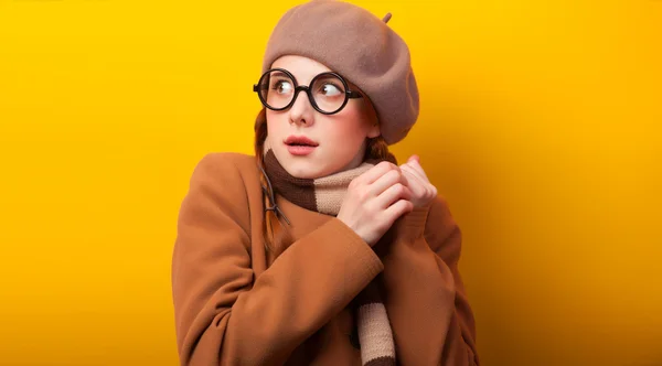 Redhead girl in coat and scarf on yellow background. — Stock Photo, Image