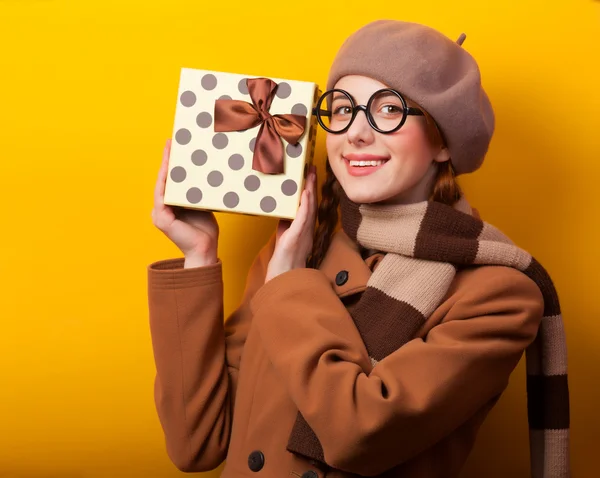 Κοκκινομάλλα κοπέλα με κιβώτιο δώρων σε κίτρινο φόντο. — Φωτογραφία Αρχείου