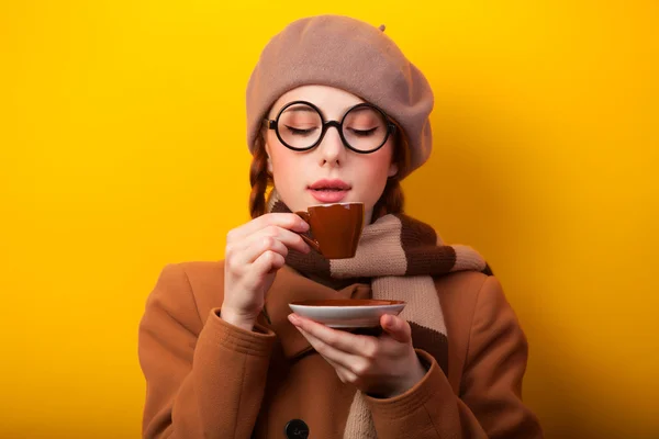 Redhead girl with coffee on yellow background — Stock Photo, Image