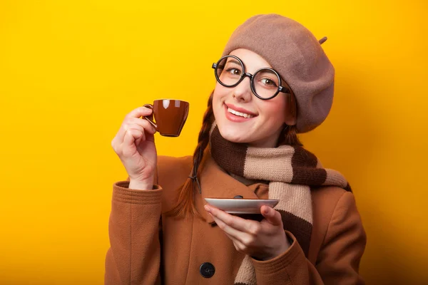 Рыжая девушка с кофе на желтом фоне — стоковое фото