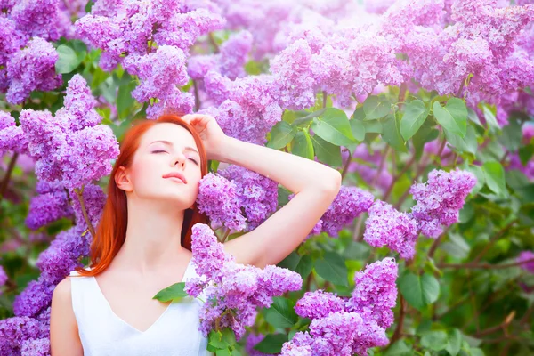 Redhead girl near lilac tree in the garden. — Stock Photo, Image