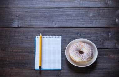 defter, çörek ve ahşap masa üstünde kalem.