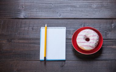 defter, çörek ve ahşap masa üstünde kalem.