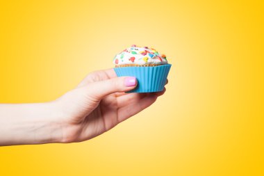 el Sarı zemin üzerine cupcake tutarak