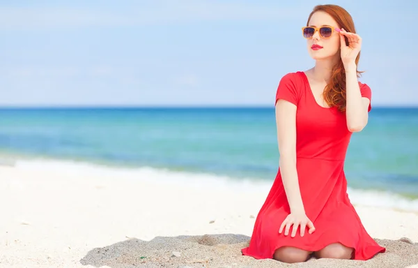 Roodharige meisje in de zonnebril op het strand — Stockfoto