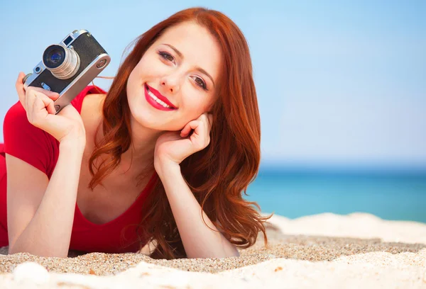 Redhead girl with camera on the beach — Stock Photo, Image