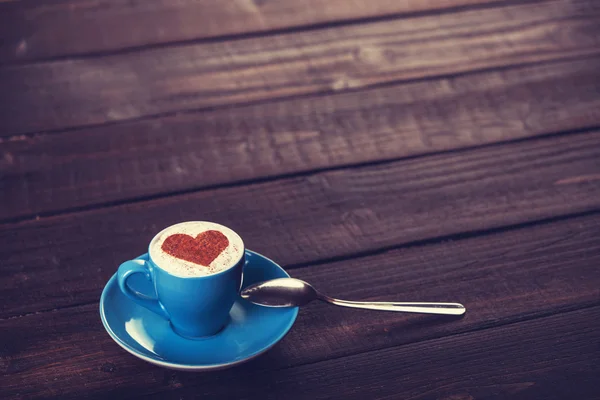 Xícara de café com coração de forma em uma mesa de madeira . — Fotografia de Stock