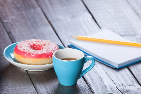 Cup of coffee with notebook and donut. — Stock Photo, Image