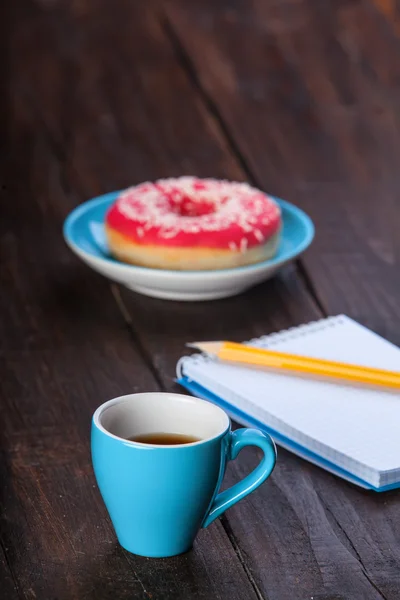 Kopje koffie met notebook en donut. — Stockfoto