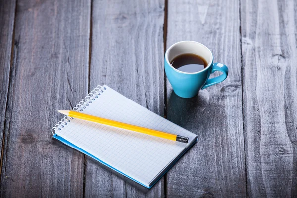 コーヒー動作ノートブックおよび鉛筆、木製テーブルの上のカップ. — ストック写真