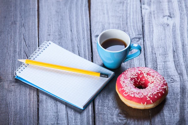 Taza de café con cuaderno y rosquilla . —  Fotos de Stock