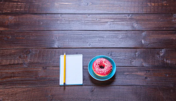 Ноутбук, пончик и карандаш на деревянном столе . — стоковое фото
