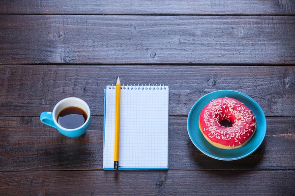 Ноутбук, пончик и карандаш на деревянном столе . — стоковое фото