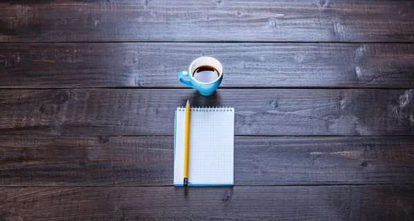 Cup of coffee with notebook and pencil, on wooden table. — Stock Photo, Image