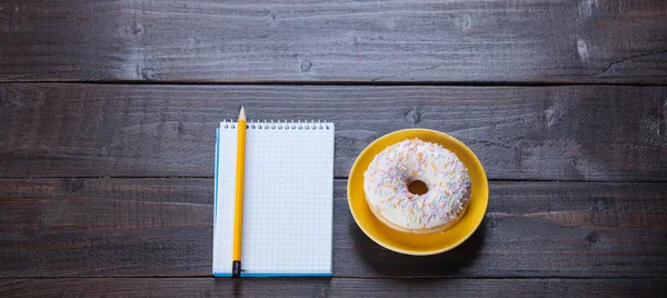 Notizbuch, Donut und Bleistift auf Holztisch. — Stockfoto