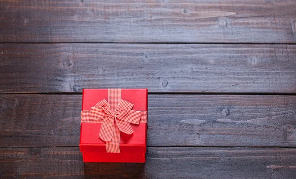 Roter Geschenkkarton auf Holztisch. Foto im Retro-Farbbild-Stil. — Stockfoto