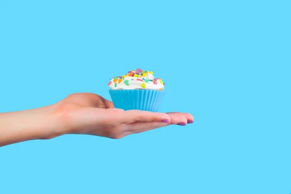 Hand holding cupcake on blue background — Stock Photo, Image