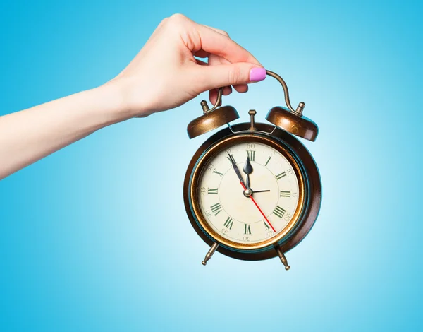 Hand holding alarm clock on blue background. — Stock Photo, Image