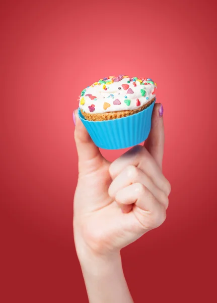 Hand holding cupcake on red background — Stock Photo, Image