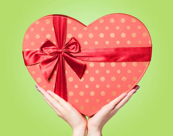 Hands holding shape heart box on green background. — Stock Photo, Image