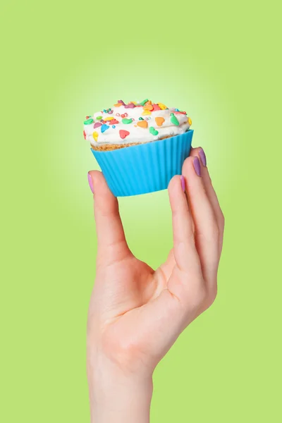 Hand holding cupcake on green background — Stock Photo, Image