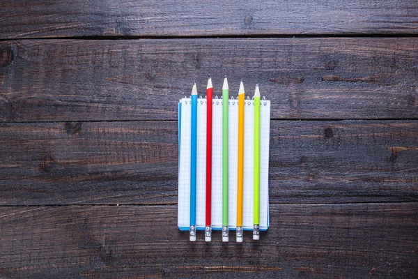 Bleistifte und Notizbuch auf Holztisch — Stockfoto