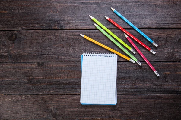 Pencils and notebook on wooden table — Stock Photo, Image