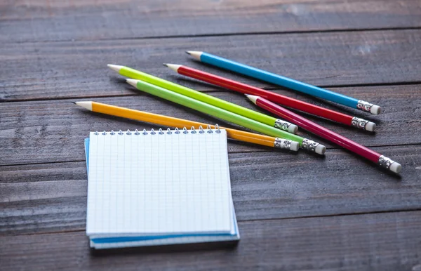 Pencils and notebook on wooden table — Stock Photo, Image