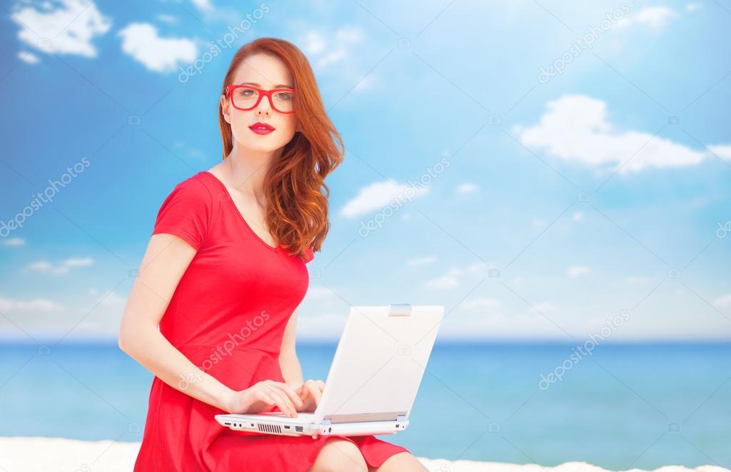 Redhead girl in the glasses with notebook on the beach