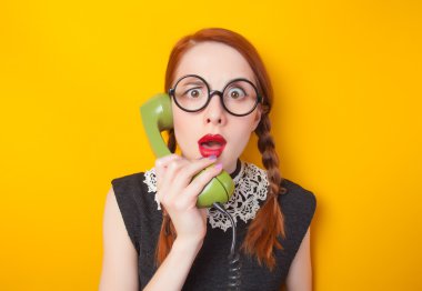 Kızıl saçlı kız sarı zemin üzerine yeşil telefon ile.