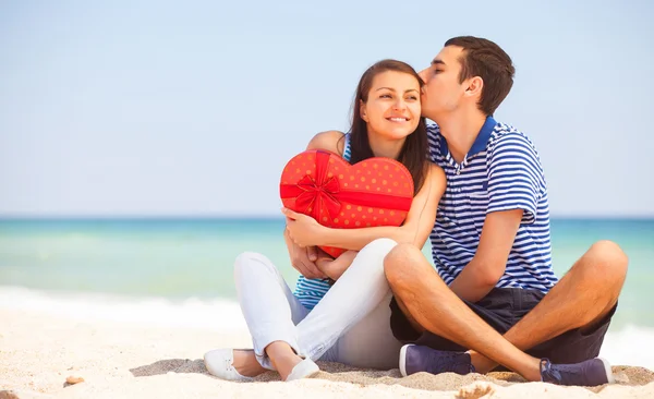 Pareja joven con regalo en la playa en el día de verano . —  Fotos de Stock