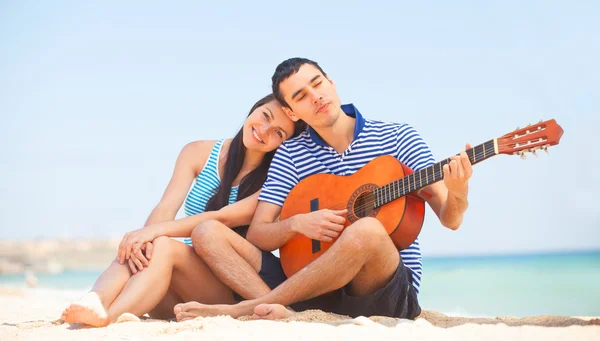 Jovem casal com guitarra na praia no dia de verão . — Fotografia de Stock