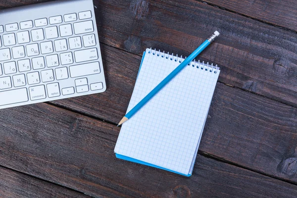 Toetsenbord, notitieboekje en potlood op houten tafel. — Stockfoto