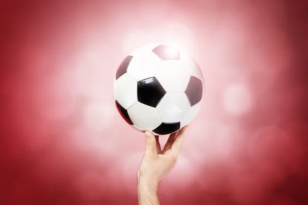 Ruka drží míč na barvu pozadí — Stock fotografie