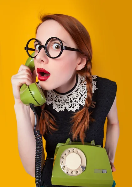 Roodharige meisje met groene telefoon op gele achtergrond. — Stockfoto