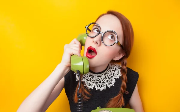 Menina ruiva com telefone verde no fundo amarelo . — Fotografia de Stock