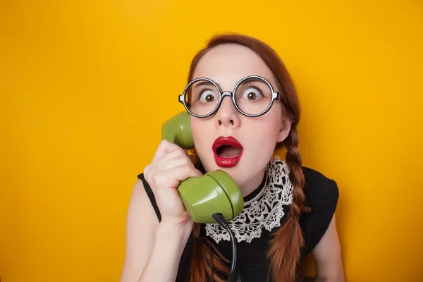 Rusovláska dívka s zelený telefon na žlutém podkladu. — Stock fotografie