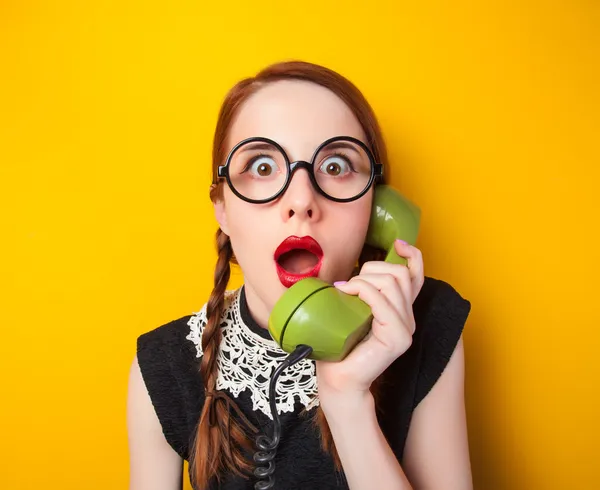 Menina ruiva com telefone verde no fundo amarelo . — Fotografia de Stock