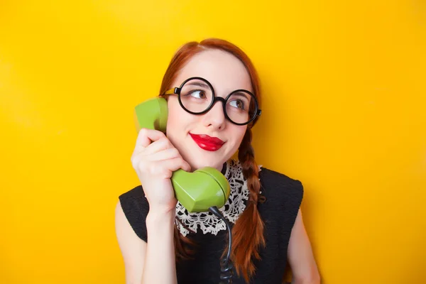 Redhead girl with green phone on yellow background. — Stock Photo, Image