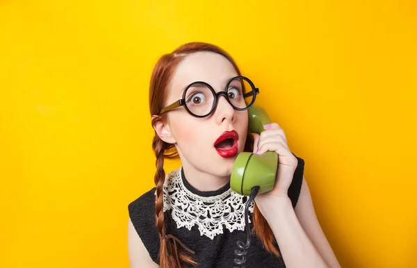 Redhead girl with green phone on yellow background. — Stock Photo, Image