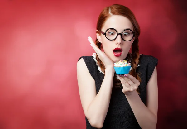 Cupcake kırmızı zemin üzerine olan Kızıl saçlı kız — Stok fotoğraf