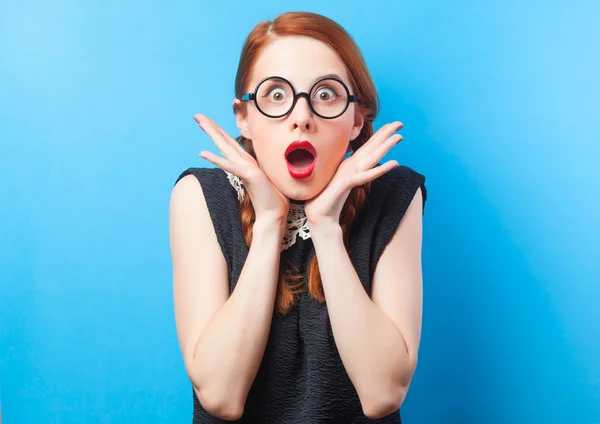 Surprised redhead girl on blue background. — Stock Photo, Image