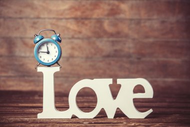 Çalar saat ve sözcük Aşk ahşap masada.