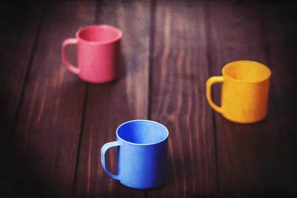 Trois tasses de couleur sur table en bois . — Photo