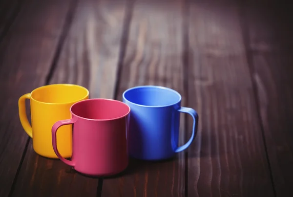 Tre färg koppar på woodent bord. — Stockfoto