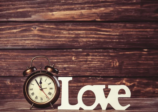 Clock with word love on wooden table. — Stock Photo, Image