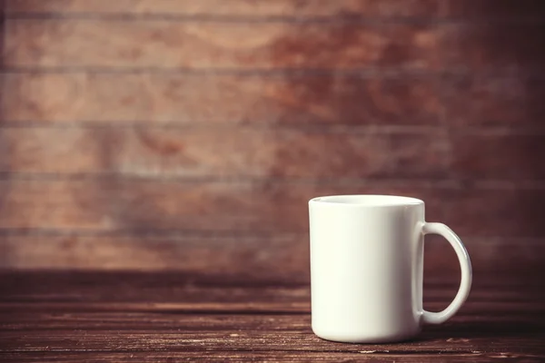 Taza blanca sobre mesa de madera. — Foto de Stock